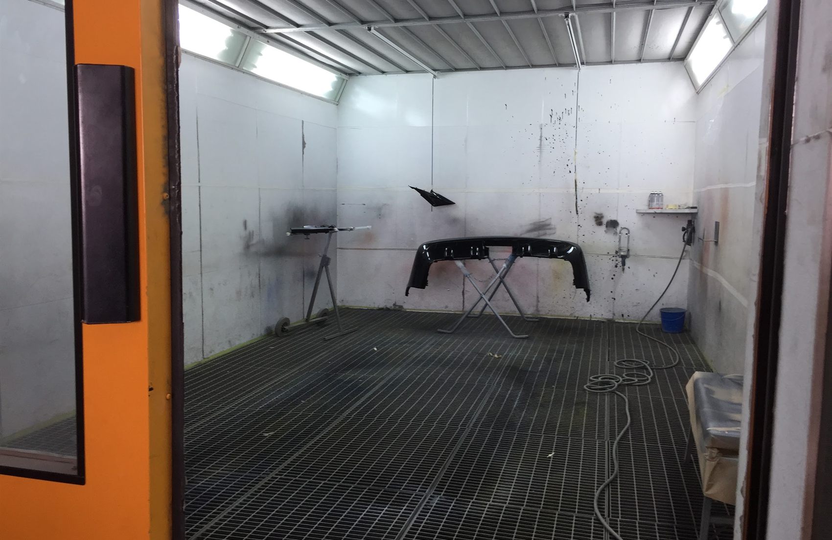 Interior de la cabina de pintura, con el suelo de rejilla y los focos a los lados